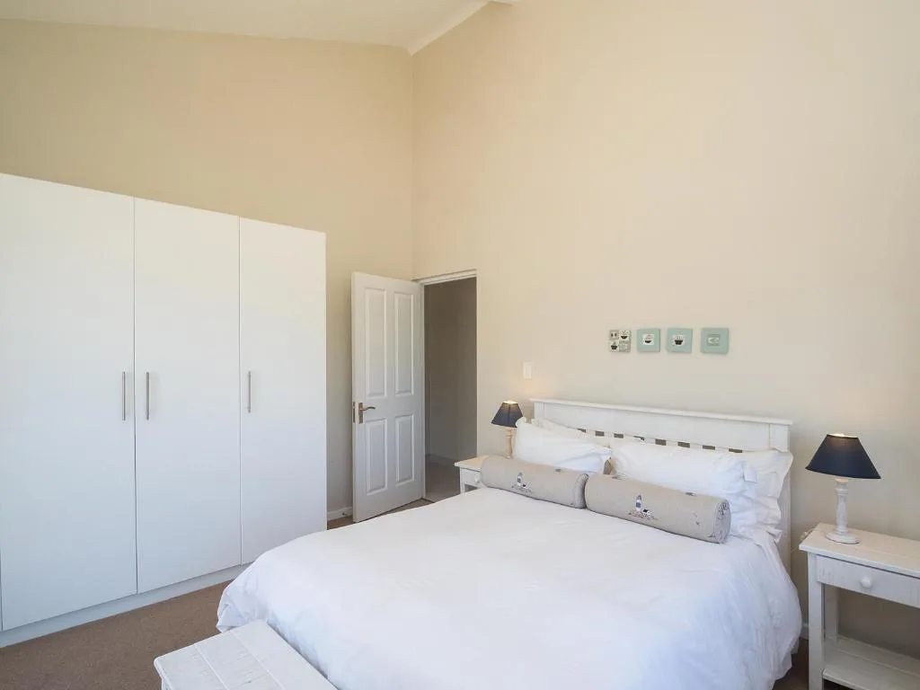 Bright bedroom with white bed, wardrobe, and side lamps