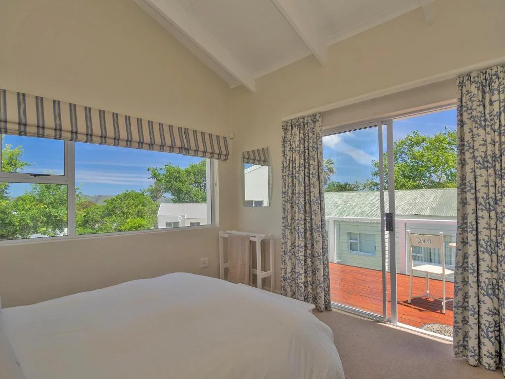 Bright bedroom with bed, large windows overlooking garden and mountains