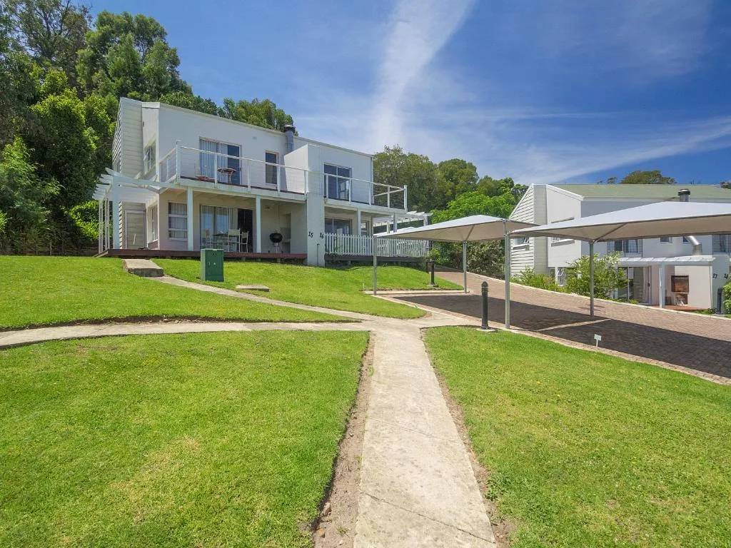 Modern white two-story house with manicured lawns and shade structures