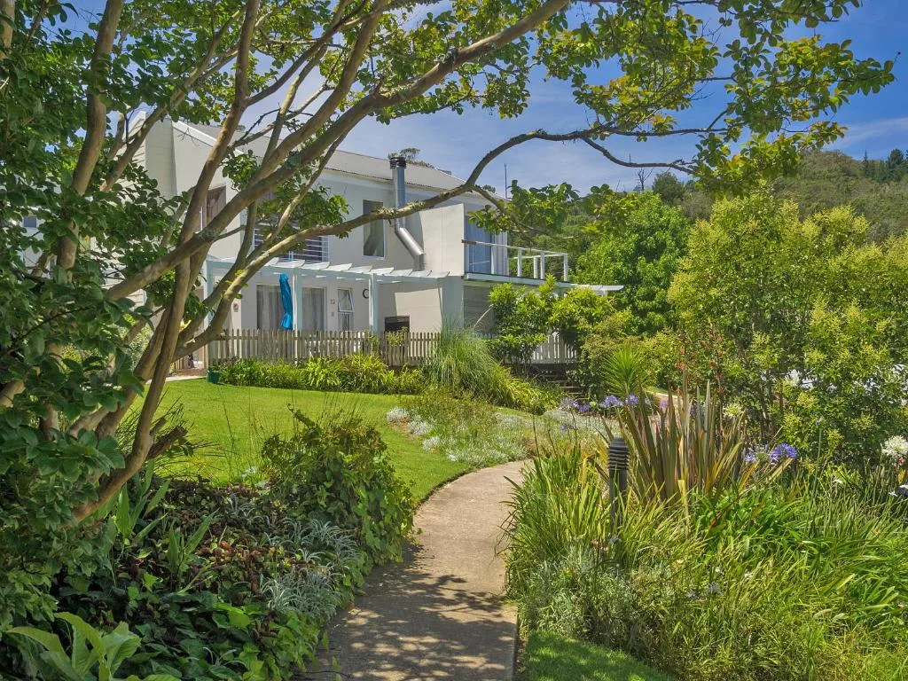 Modern white holiday home with manicured garden and mature trees