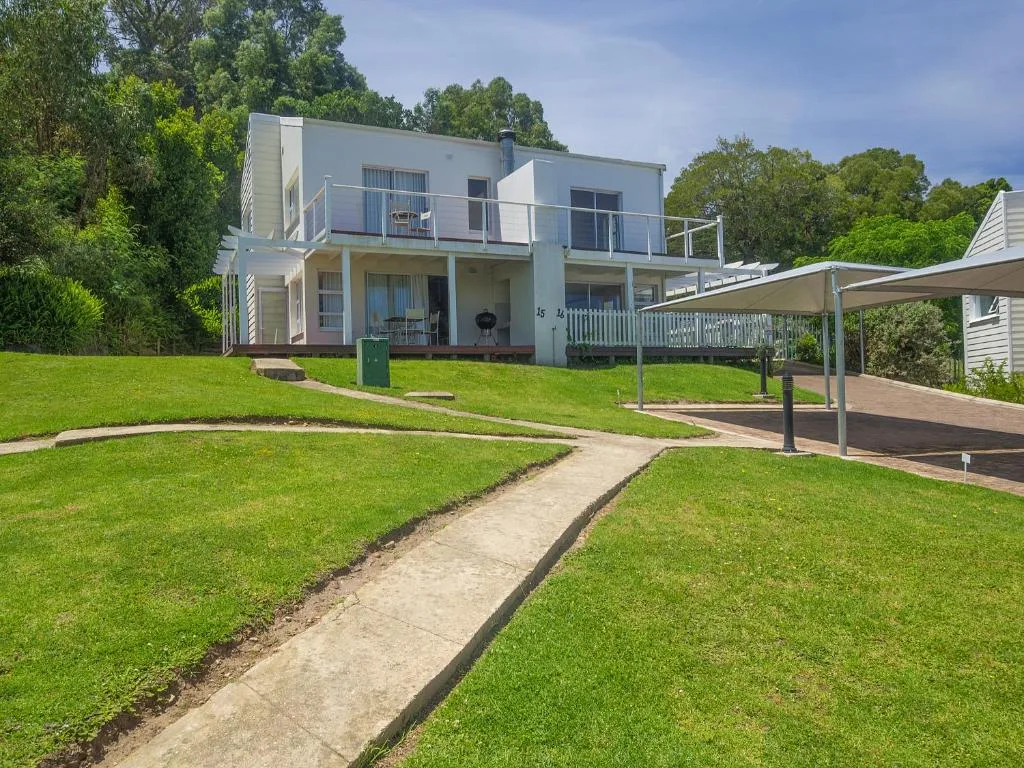 Modern two-story white house with green lawn and tree-lined surroundings