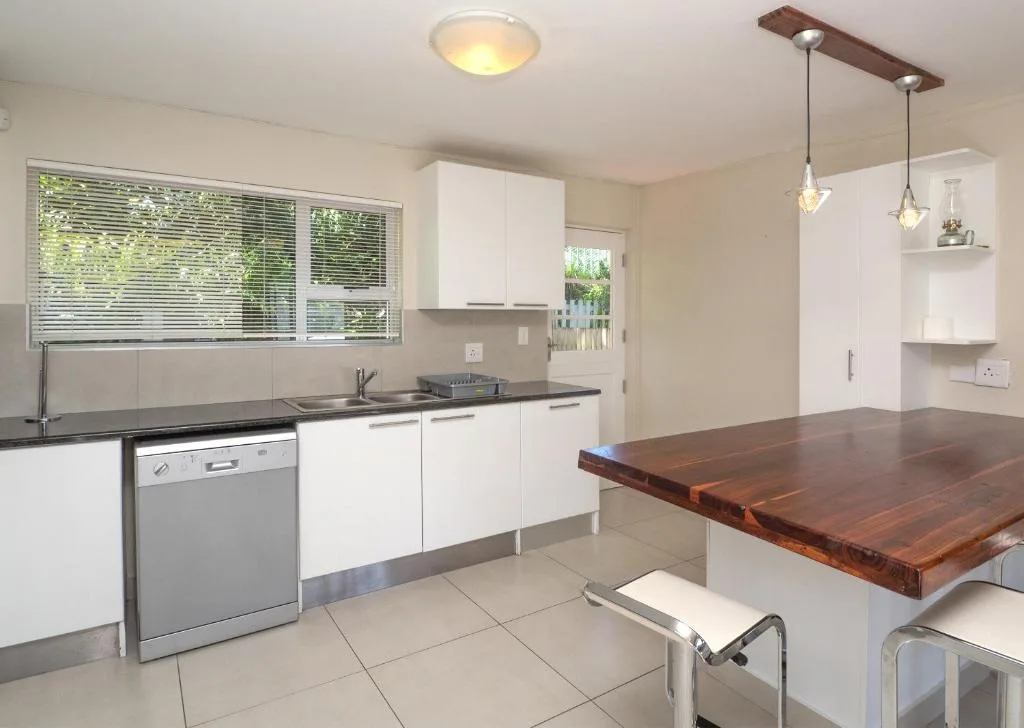 Modern kitchen with white cabinetry, stainless steel appliances, and wooden dining counter