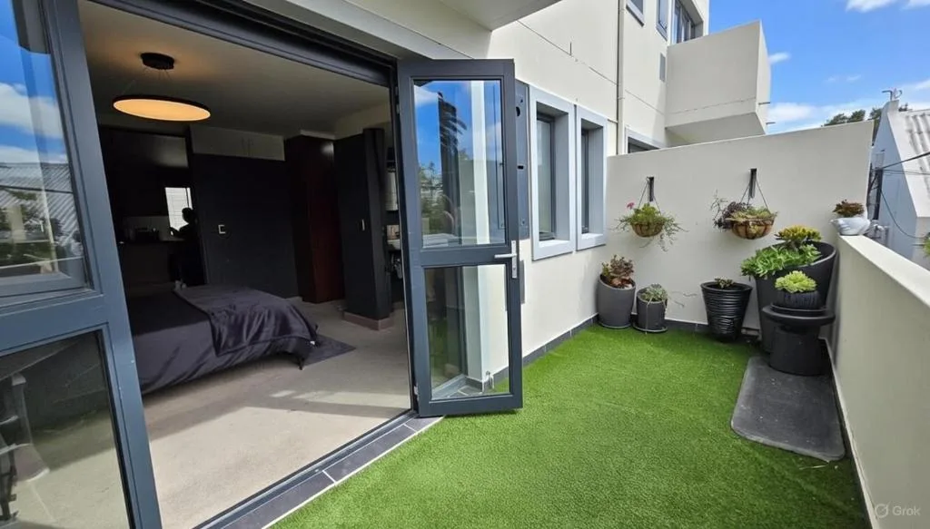 Modern balcony with artificial grass, potted plants, and ocean views