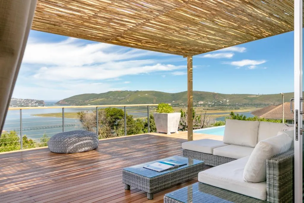 Spacious wooden deck with lounge seating overlooking lagoon and mountains