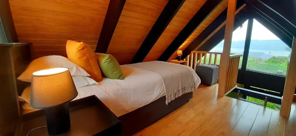 Spacious bedroom with twin beds, wooden beams, and mountain lagoon views