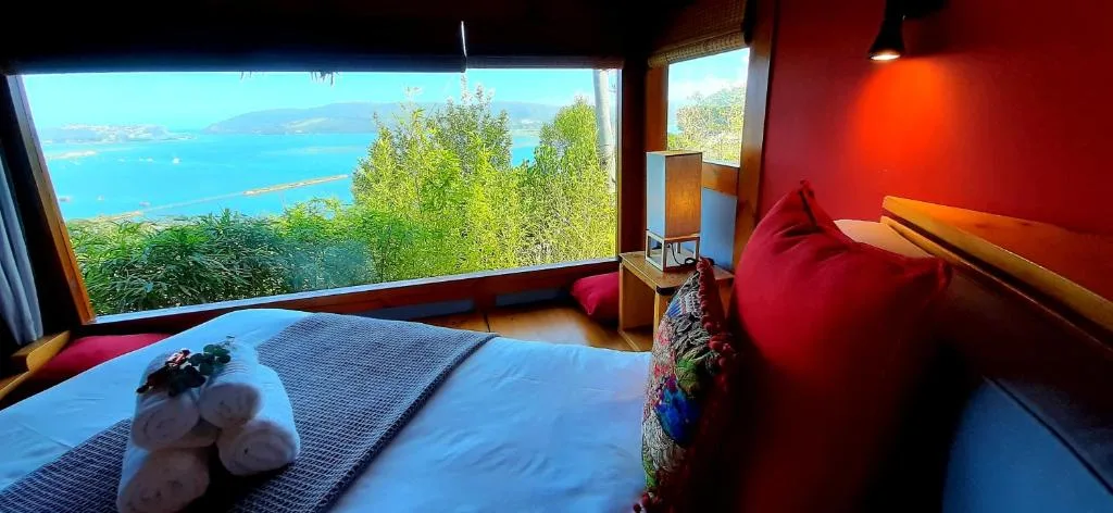 Bedroom with ocean view through large windows, red accents, modern decor