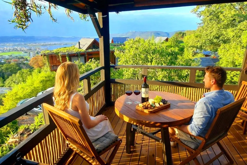 Couple enjoying wine and food on wooden deck with lagoon views