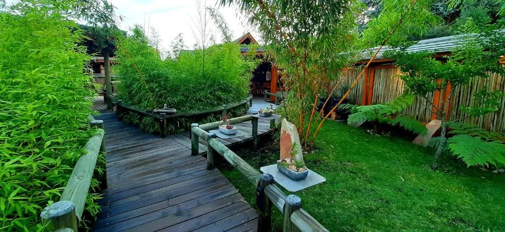 Wooden boardwalk through lush garden with seating area and landscaped grounds