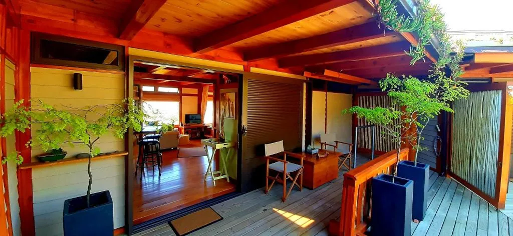 Wooden deck with vibrant red and yellow architecture, modern furniture, and potted plants