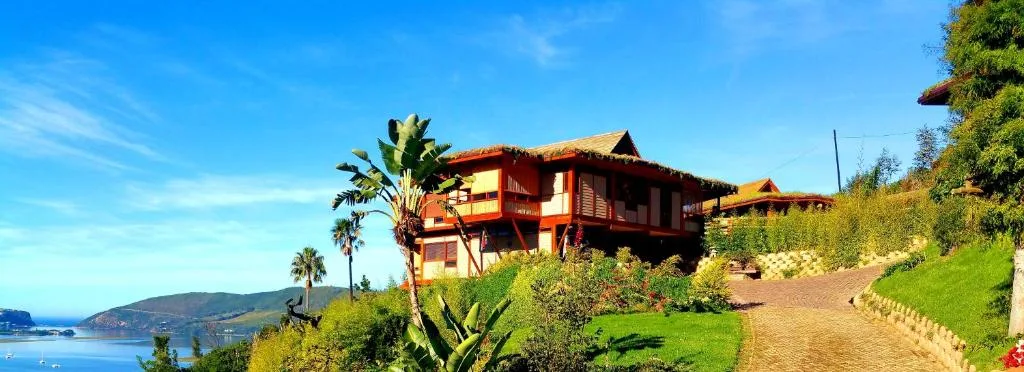 Red and cream wooden cottage with ocean view overlooking Knysna lagoon