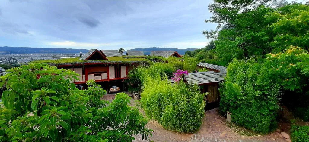 Red and wood cottage surrounded by lush gardens with mountain valley views