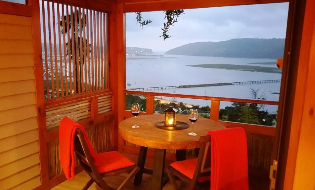 Lagoon and mountain vista through red-framed deck windows at sunset