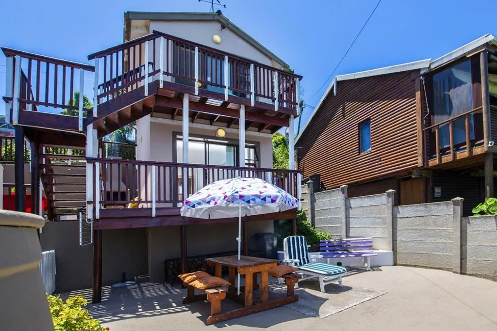 Modern multi-level home with wooden deck, umbrella, and outdoor seating area