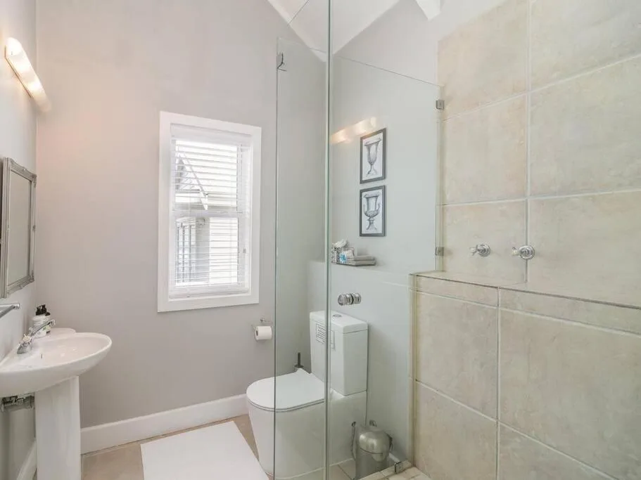 Modern bathroom with pedestal sink, toilet, and glass shower enclosure