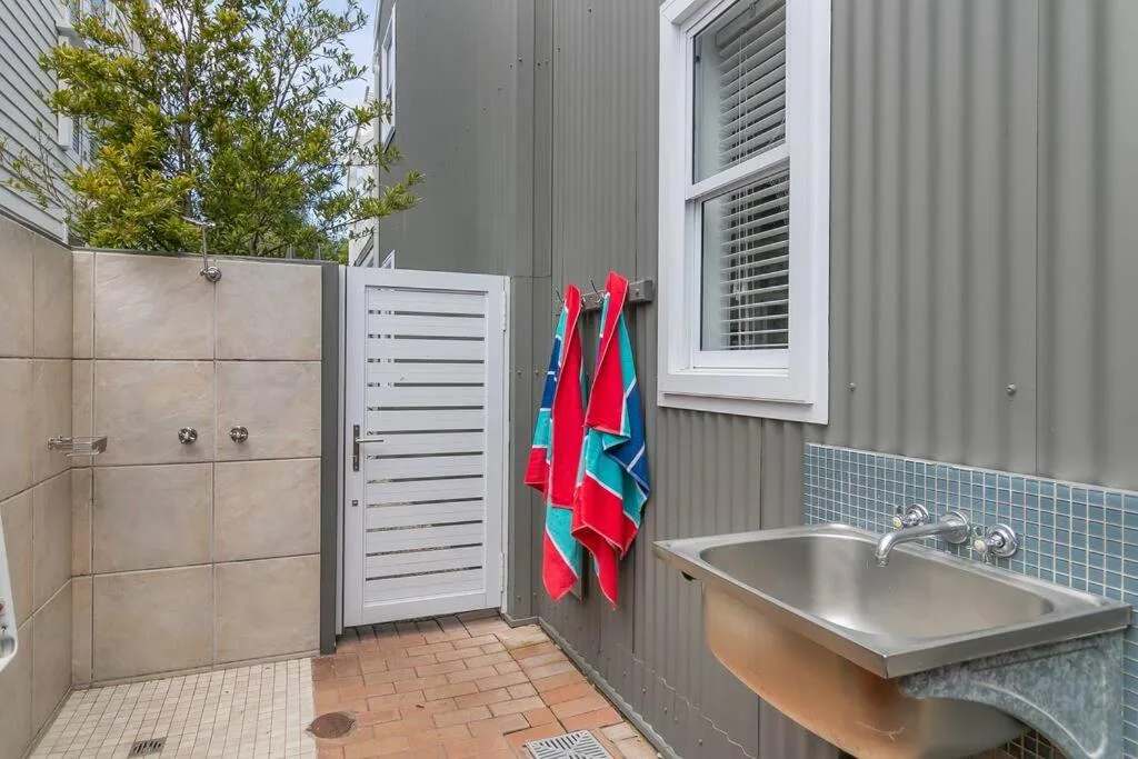 Modern bathroom with walk-in shower, tiled walls, and stainless steel sink