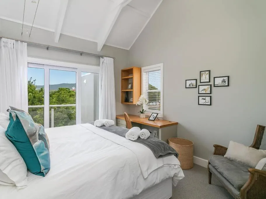 Bright bedroom with mountain views through large windows and white linens