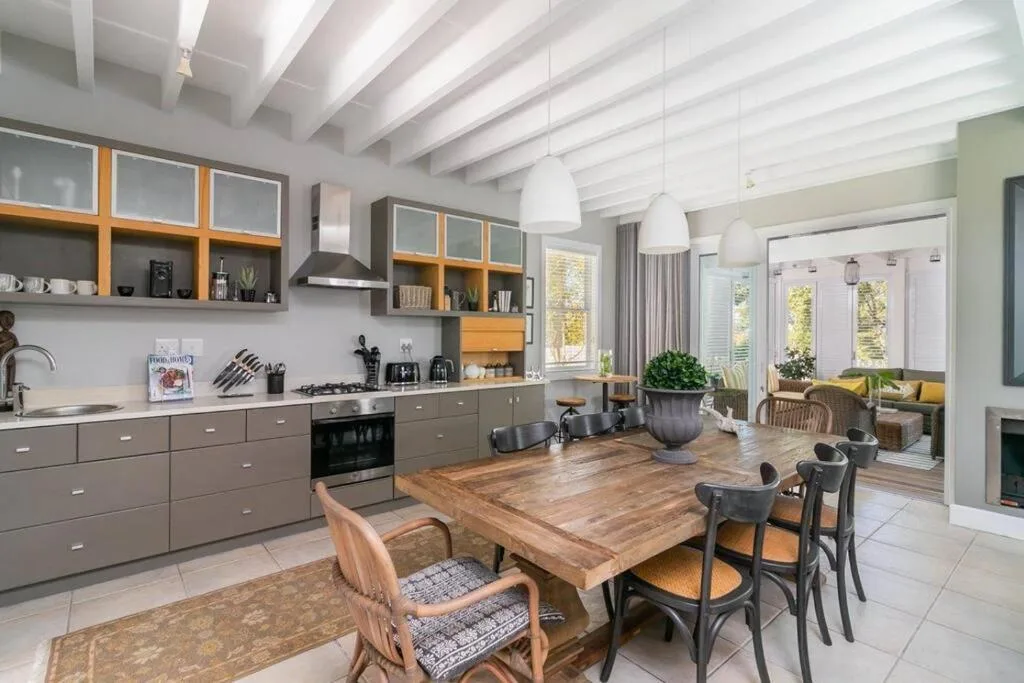 Modern open-plan kitchen with dining area, wooden beams, and large windows
