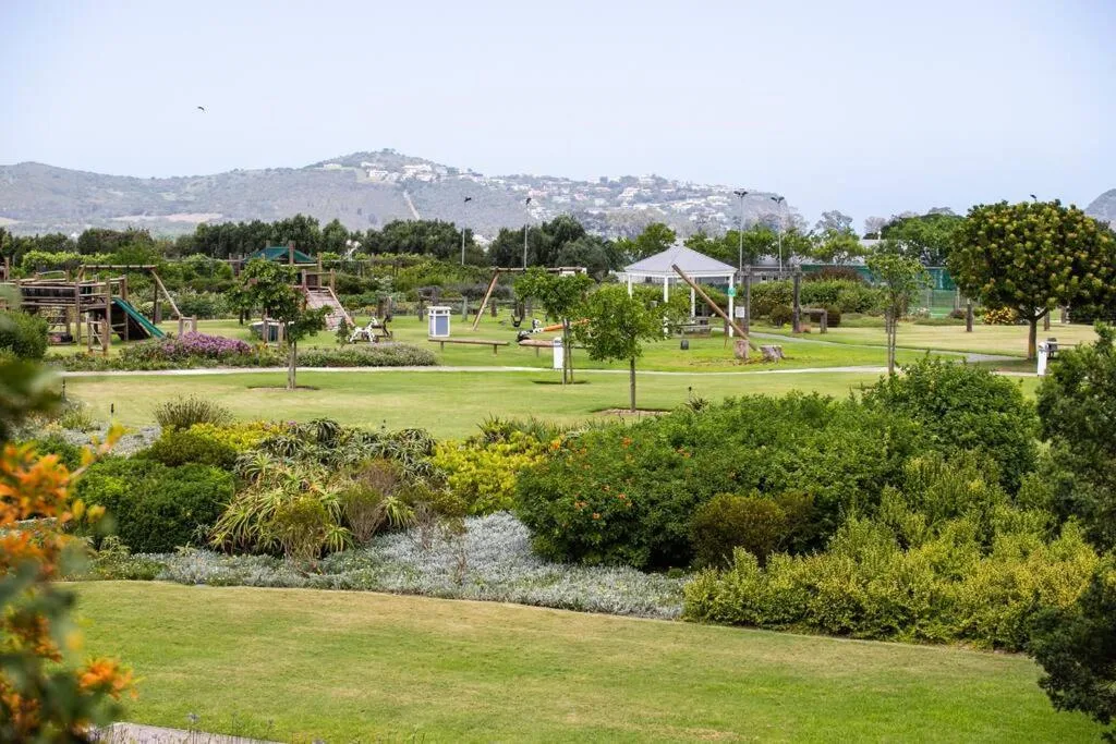 Expansive garden with mountains, playground, and lush landscaping beyond