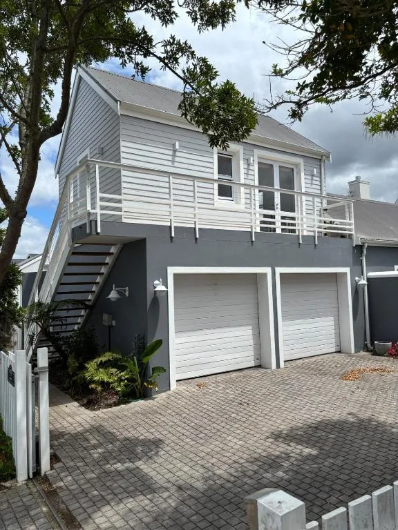 Modern white and grey house with double garage and elevated deck on paved driveway