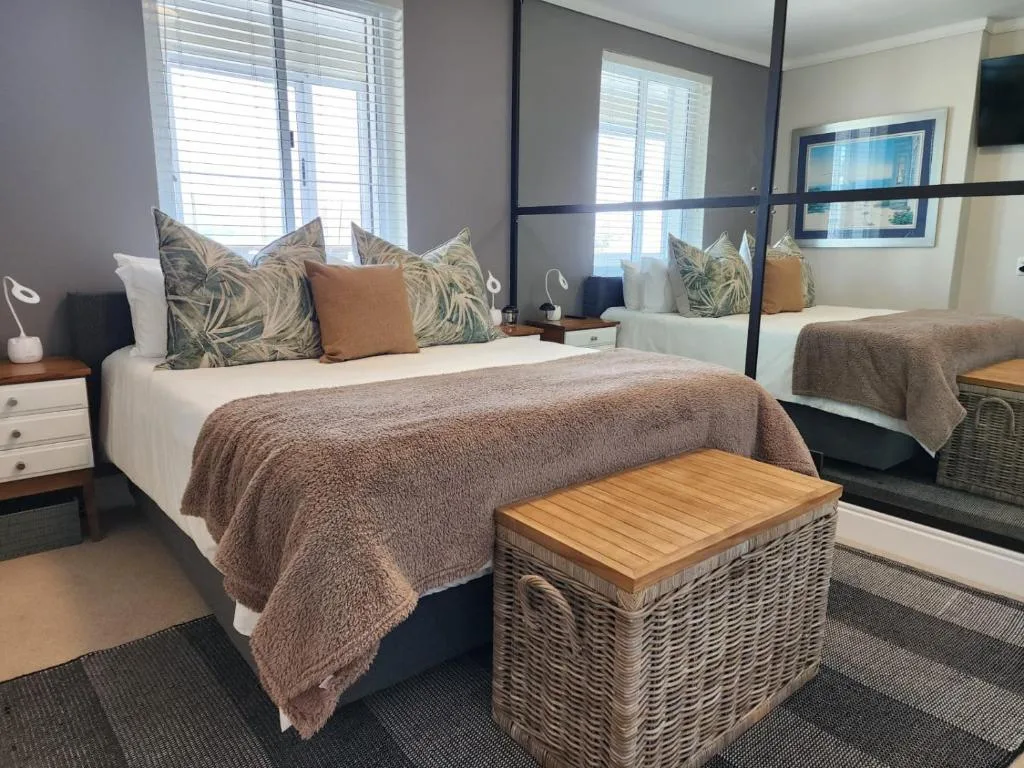 Spacious bedroom with queen bed, decorative pillows, and mirrored wardrobe