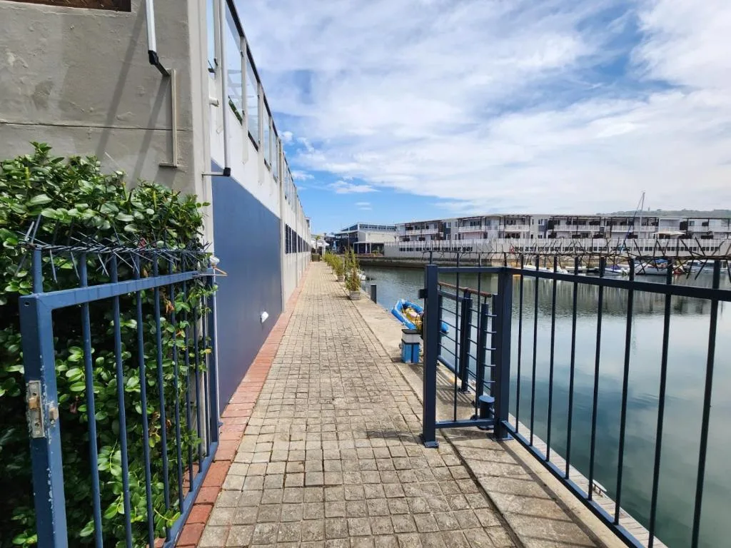 Waterfront promenade with railing overlooking calm lagoon waters and moored boats
