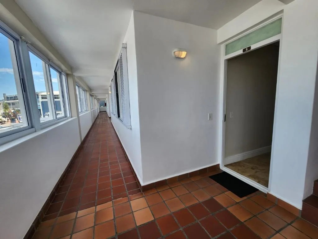 Long corridor with terracotta tiles and town views through windows