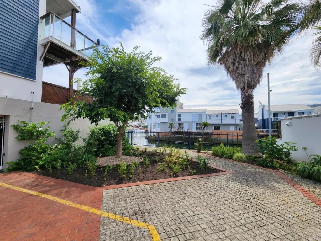 Waterfront apartment building with palm tree and landscaped garden courtyard