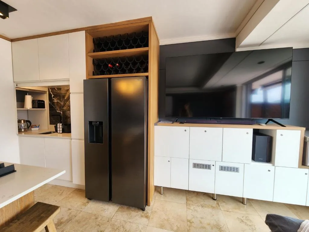 Modern kitchen with black side-by-side refrigerator and white cabinetry storage