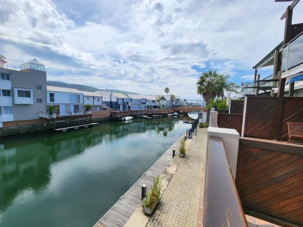 Waterfront lagoon view with modern apartments, boats, palm trees, mountains