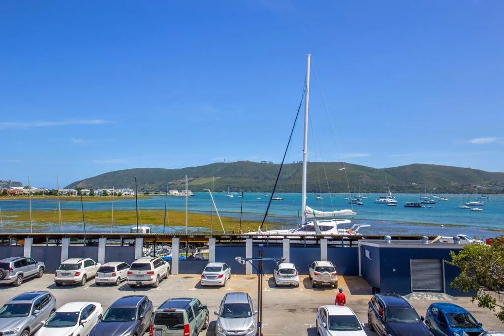 Turquoise bay waters with sailboats and tree-covered mountains beyond