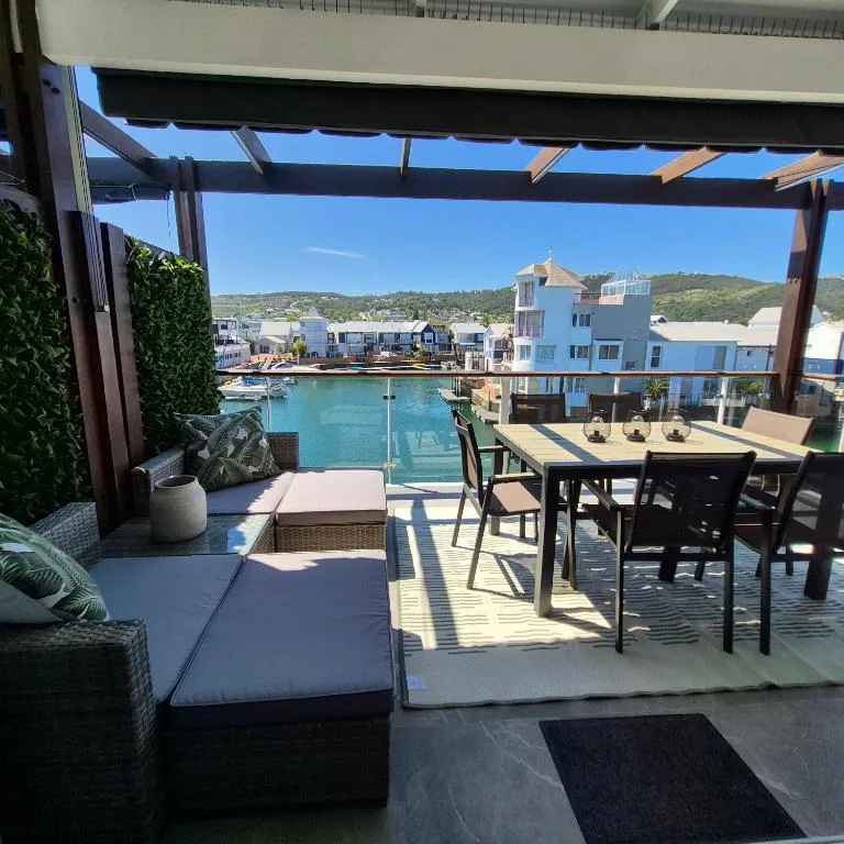 Waterfront deck with dining table overlooking turquoise lagoon and hills