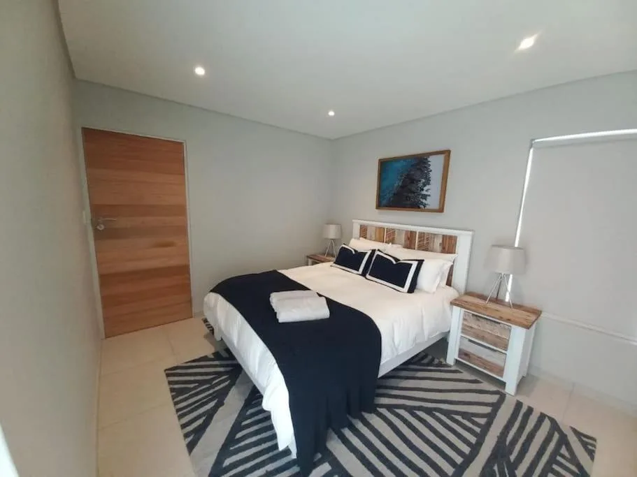 Modern bedroom with queen bed, white headboard, black and white striped rug