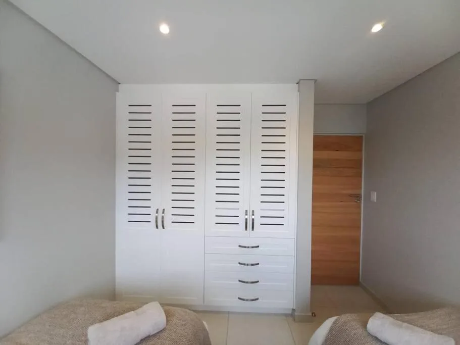 Modern bedroom with twin beds and large white built-in wardrobe storage