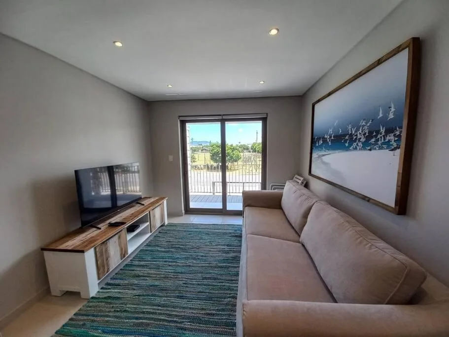 Modern lounge with beige sofa, TV, and scenic lagoon view doors