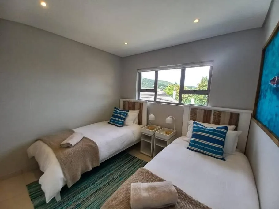Twin bedroom with striped pillows, wooden headboards, mountain views through windows