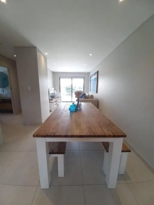 Modern dining table with wooden top and white base in bright open-plan apartment