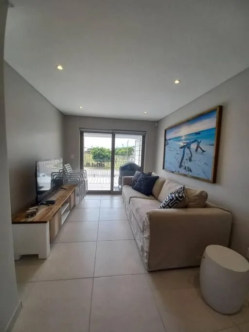 Modern lounge with beige sofa, TV, and sliding glass doors to deck