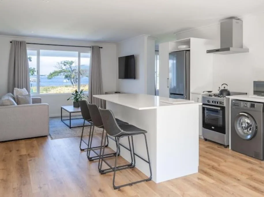 Modern open-plan kitchen with white island, stainless steel appliances, and lagoon views