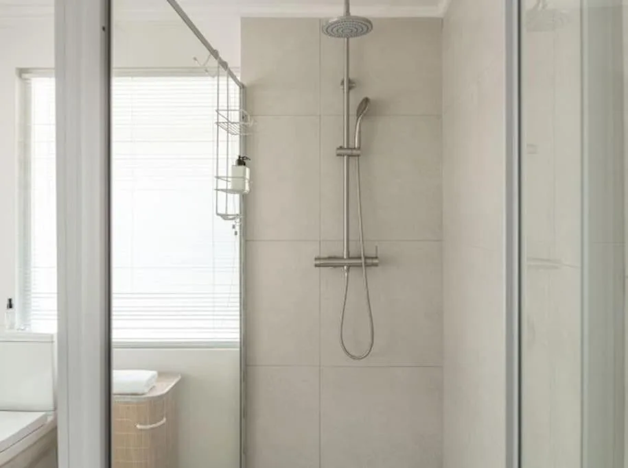 Modern shower with rainfall head and handheld sprayer in tiled enclosure