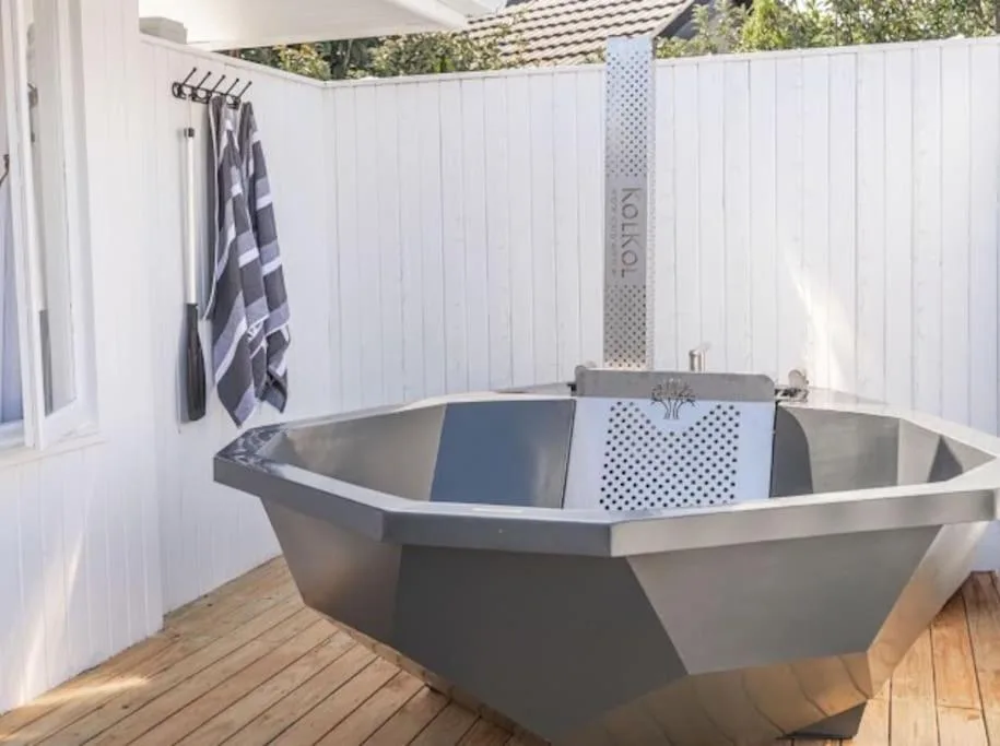 Modern freestanding bathtub on wooden deck with white privacy screens