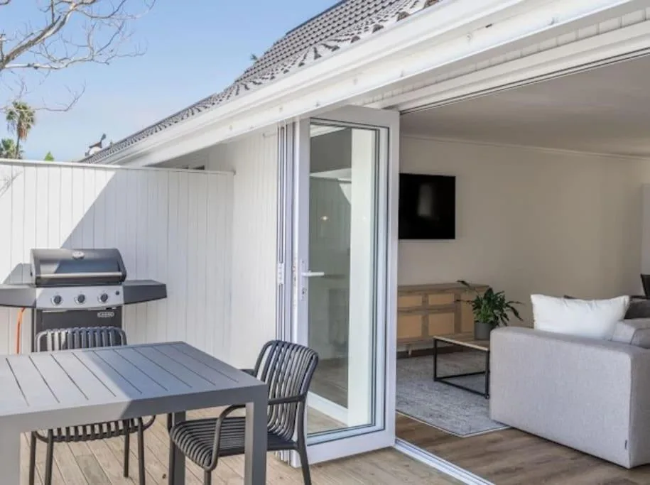 Modern deck with dining table, chairs, and built-in braai overlooking lagoon