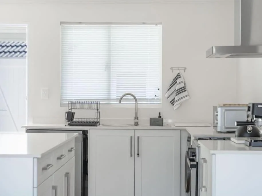 Modern kitchen with white cabinetry, stainless steel sink, and window overlooking lagoon