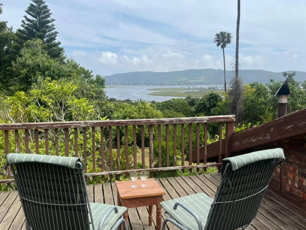 Scenic lagoon and mountain vista from wooden deck with chairs
