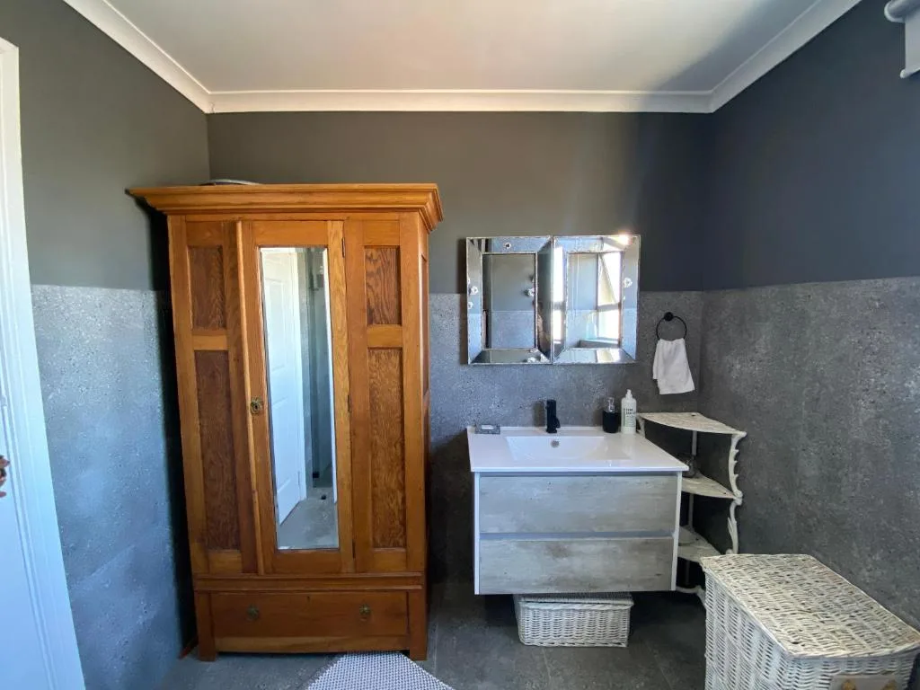 Bathroom with wooden wardrobe, white vanity sink, and mirrored cabinet