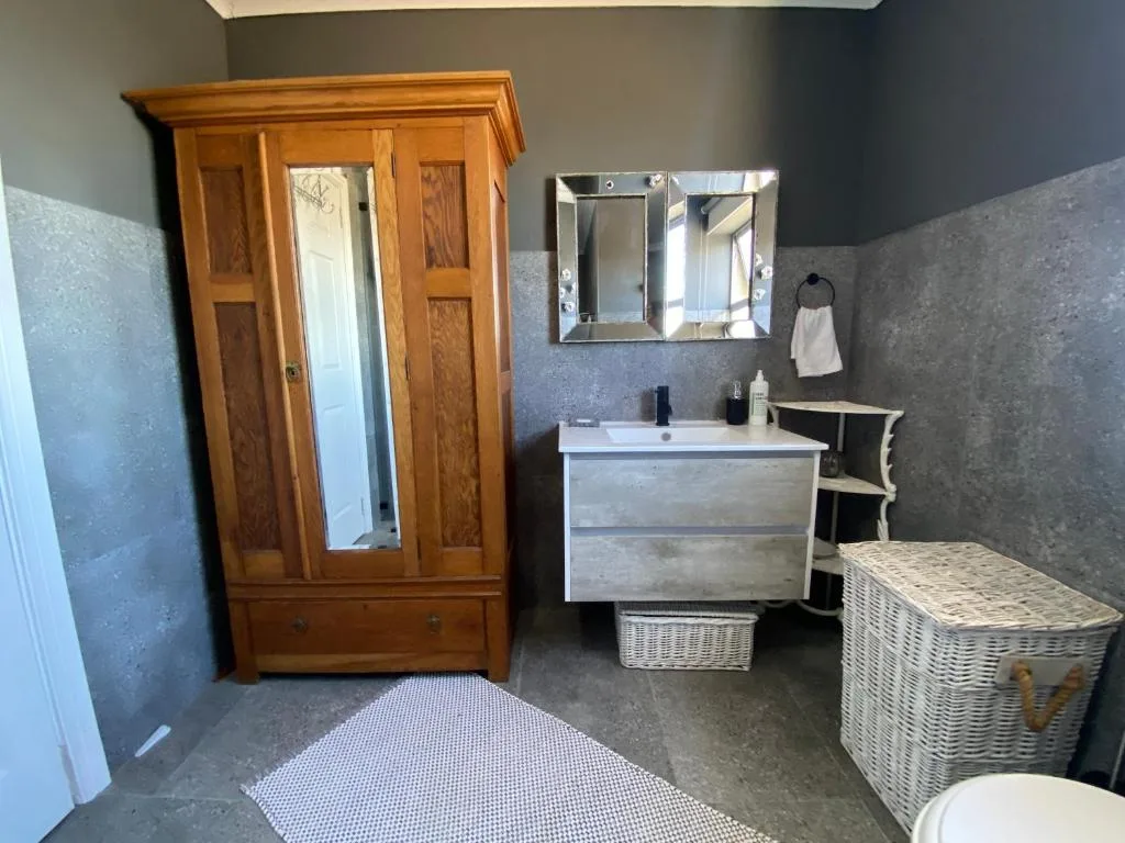 Bathroom with vanity sink, mirror, wooden wardrobe, and storage baskets