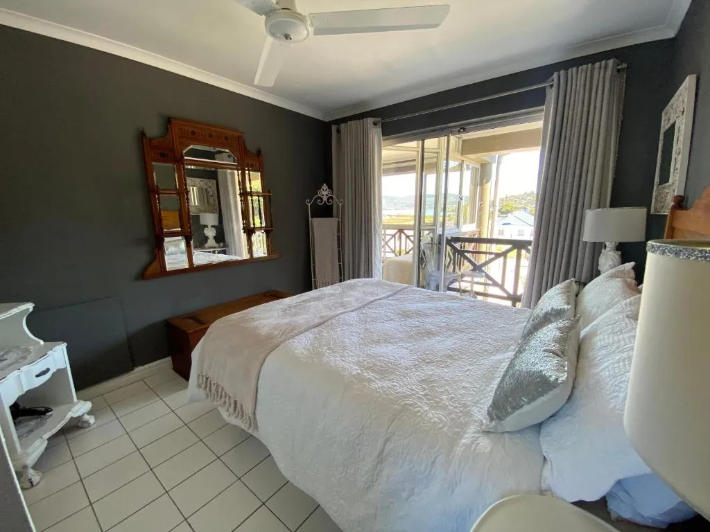Spacious bedroom with queen bed, dark accent wall, and balcony access with views