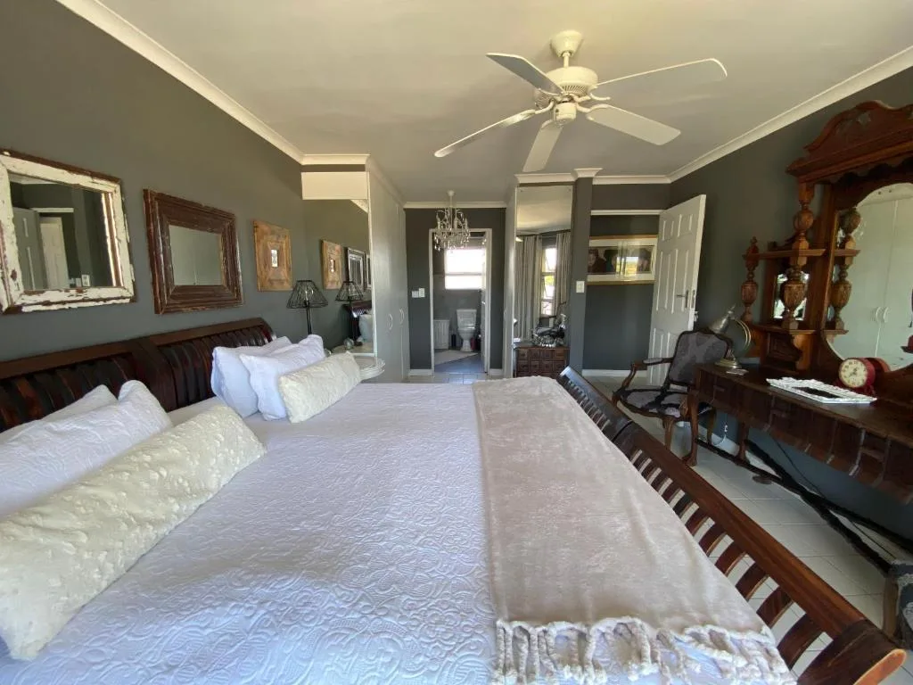 Spacious master bedroom with two beds, ceiling fan, and elegant wood furnishings