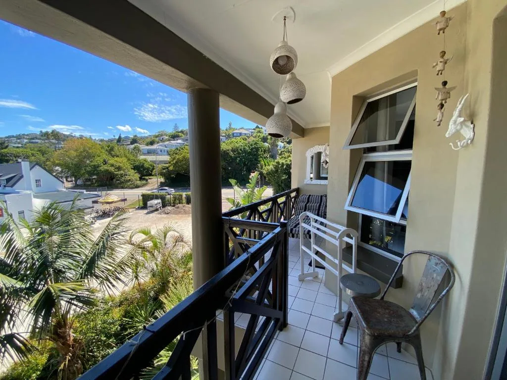 Covered balcony with black railings overlooking Knysna town and hills