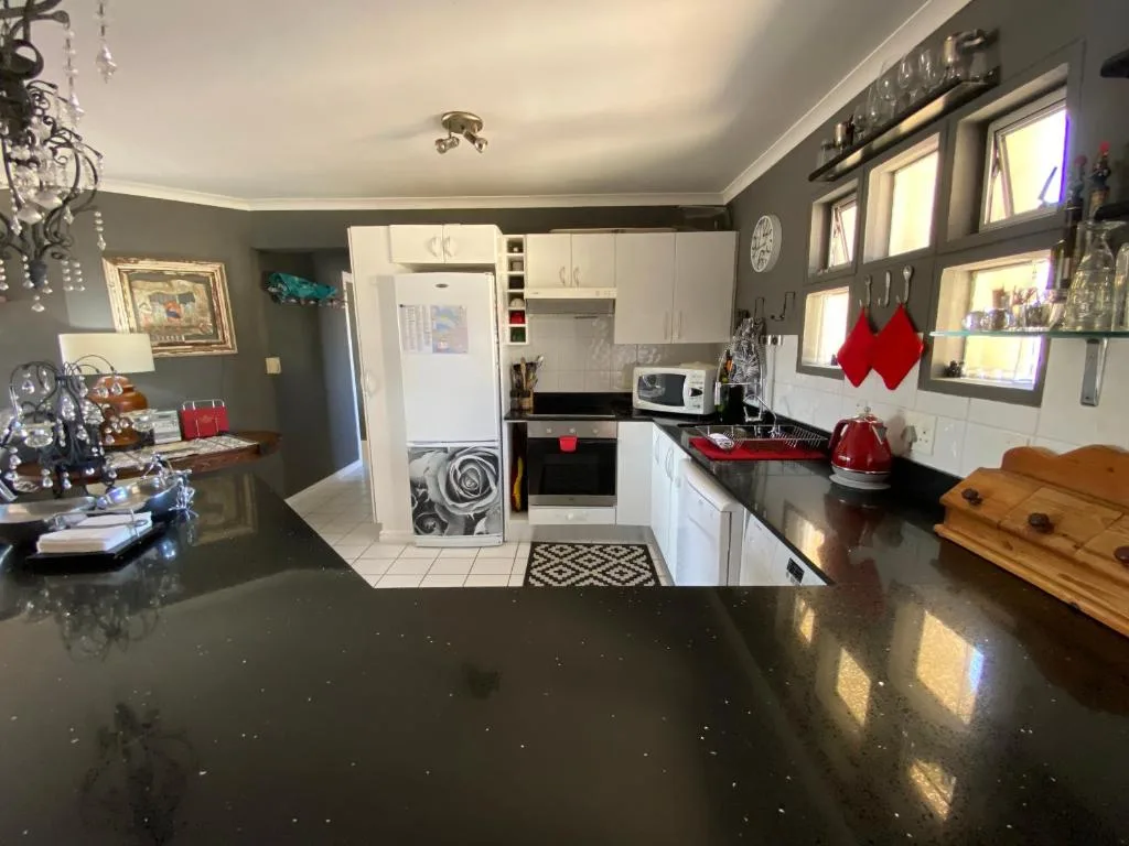 Modern kitchen with white cabinetry, black countertops, and stainless steel appliances