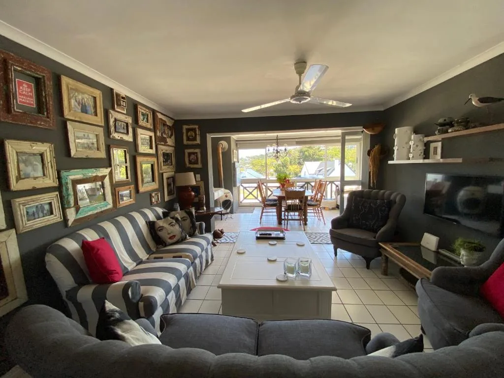 Spacious lounge with striped sofa, dark walls, gallery frames, and ocean views through glass doors